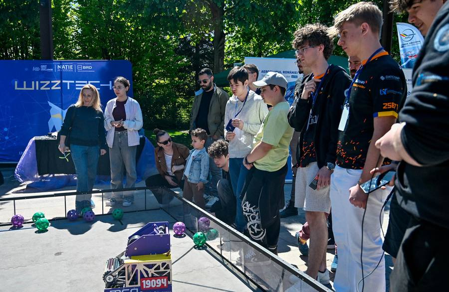 Visitors watching a robotics match next to the WizzTech stand